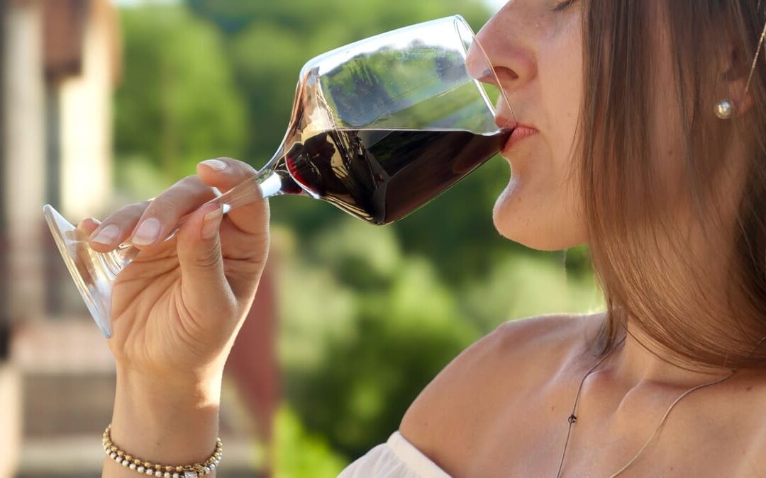 woman sipping red wine from wine glass